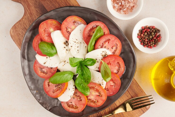 Kostenlose Foto frischer italienischer salat antipasti namens caprese mit büffelmozzarella, tomatenscheiben und basilikum mit olivenöl. zutaten für vegetarischen caprese-salat. italienisches essen. draufsicht. rustikaler stil.