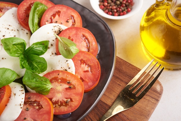 Frischer italienischer Salat Antipasti namens Caprese mit Büffelmozzarella, Tomatenscheiben und Basilikum mit Olivenöl. Zutaten für vegetarischen Caprese-Salat. Italienisches Essen. Draufsicht. Rustikaler Stil.