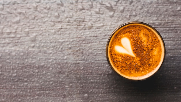 Frischer Kaffee mit Herz Lattekunst auf Wassertropfenhintergrund
