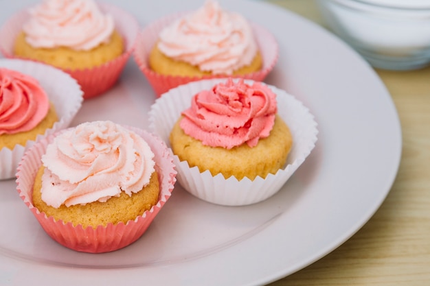 Frischer kleiner Kuchen mit rosafarbener Buttercremezuckerglasur auf Platte