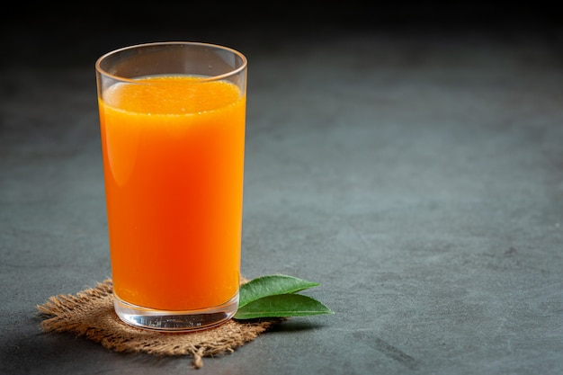 Kostenloses Foto frischer orangensaft im glas auf dunklem hintergrund