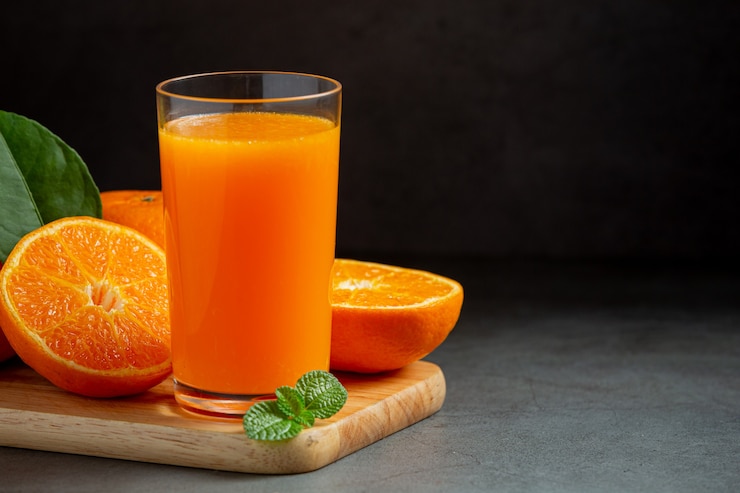 Kostenlose Foto frischer orangensaft im glas auf dunklem hintergrund