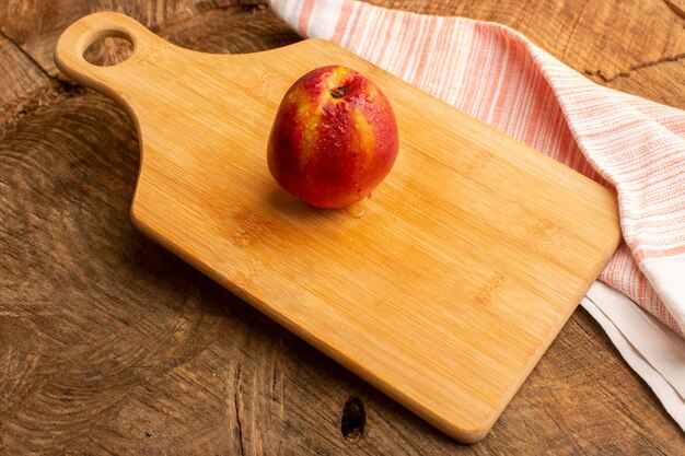 Frischer Pfirsich der Vorderansicht auf Holzschreibtisch