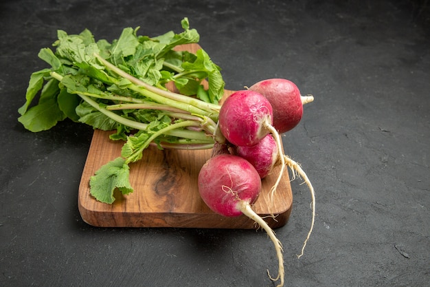 Frischer Rettich der Vorderansicht mit Grün auf einem frischen reifen Salat des dunklen Tisches frisch