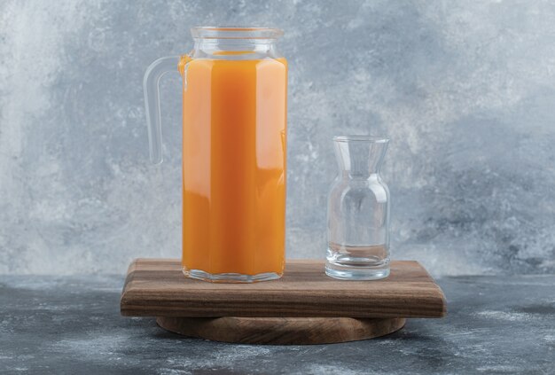 Frischer Saft und leeres Glas auf Holzbrett.