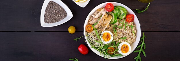 Frischer Salat. Frühstücksschüssel mit Haferflocken, Hähnchenfilet, Tomate, Salat, Microgreens und gekochtem Ei. Gesundes Essen. Vegetarische Buddha-Schüssel.