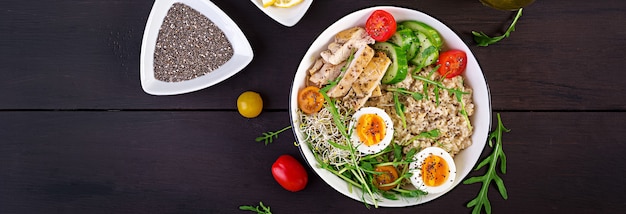 Frischer Salat. Frühstücksschüssel mit Haferflocken, Hähnchenfilet, Tomate, Salat, Microgreens und gekochtem Ei. Gesundes Essen. Vegetarische Buddha-Schüssel.