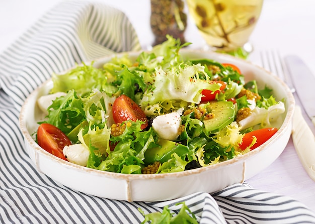 Frischer Salat mit Avocado, Tomate, Oliven und Mozzarella in einer Schüssel. Fitness Essen. Vegetarische Mahlzeit.