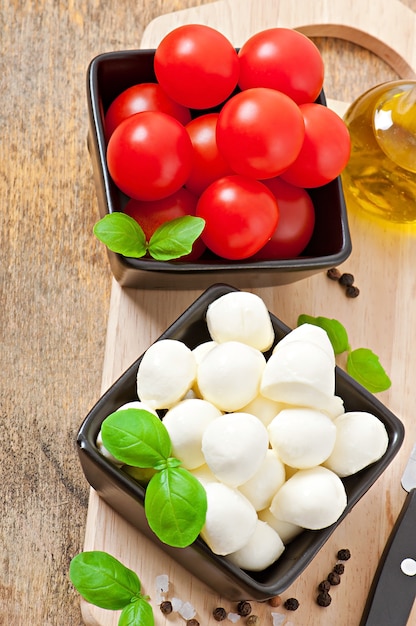 Kostenloses Foto frischer salat mit kirschtomaten, basilikum, mozzarella und schwarzen oliven.