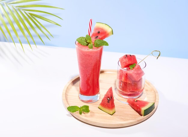 Frischer Wassermelonensaft und Wassermelonscheiben auf pastellfarbenem Hintergrund Kühlgetränk Sommergetränk