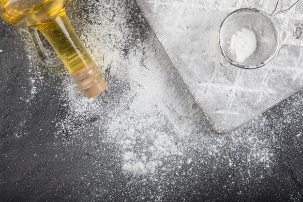 Frischer Weizenboden verschüttet auf Holzbrett mit Glas Öl