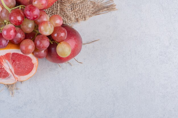 Frisches Bio-Obst. Apfel, Trauben und Mandarinen auf grauem Hintergrund.