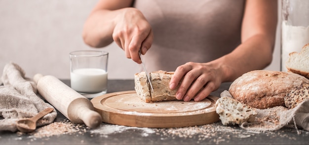 frisches Brot in den Händen Nahaufnahme auf altem hölzernen Hintergrund