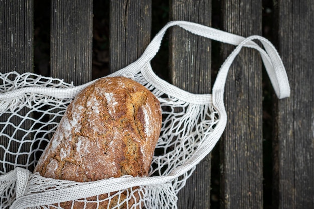 Kostenloses Foto frisches brot in einer einkaufstasche auf einer hölzernen hintergrundebene lag