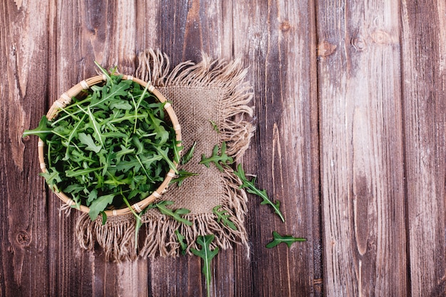 Frisches Essen, gesundes Leben. Grüner Arugula diente in der Schüssel auf rustikalem Hintergrund