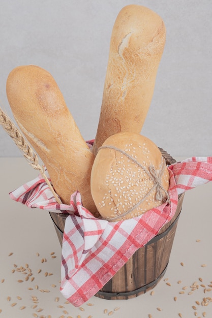 Frisches gebäck des brotes auf holzkorb mit tischdecke