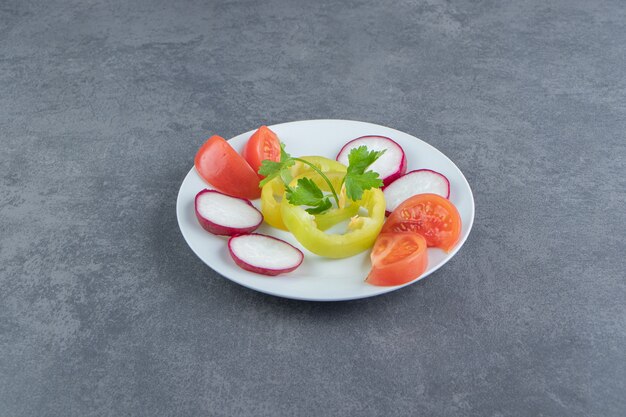 Frisches gehacktes Gemüse auf weißem Teller.