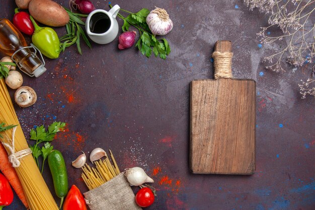 Kostenloses Foto frisches gemüse von oben mit roher pasta und schreibtisch auf dunklem, reifem essenssalat