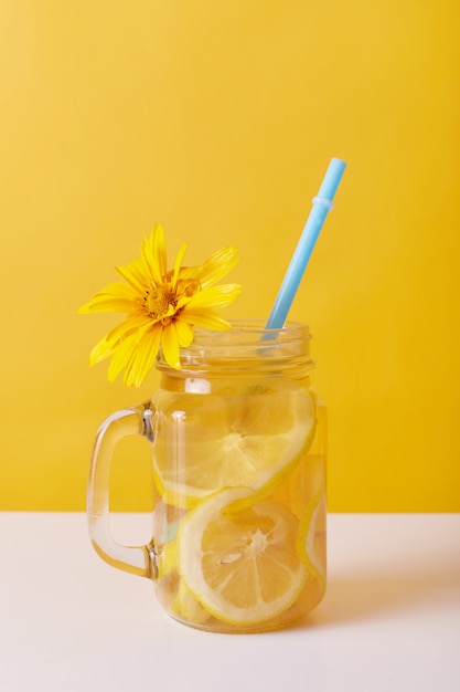 Frisches Getränk mit Zitrone, Glas mit gelber Blume verziert