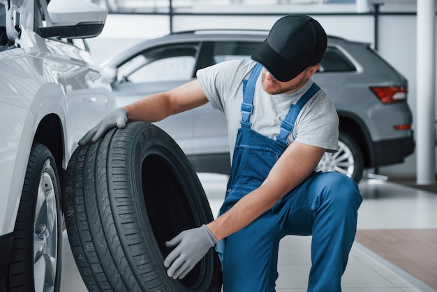 Frisches Material. Mechaniker hält einen Reifen in der Reparaturwerkstatt. Austausch von Winter- und Sommerreifen