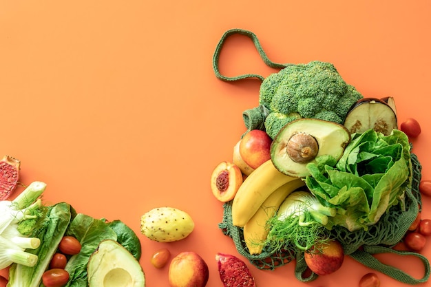 Frisches Obst und Gemüse auf farbigem Hintergrund flach gelegt