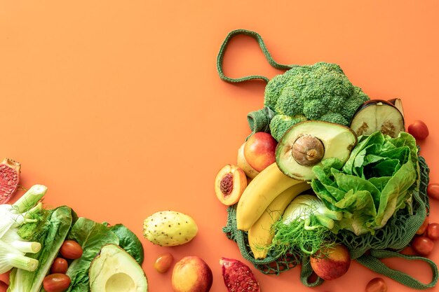 Frisches Obst und Gemüse auf farbigem Hintergrund flach gelegt
