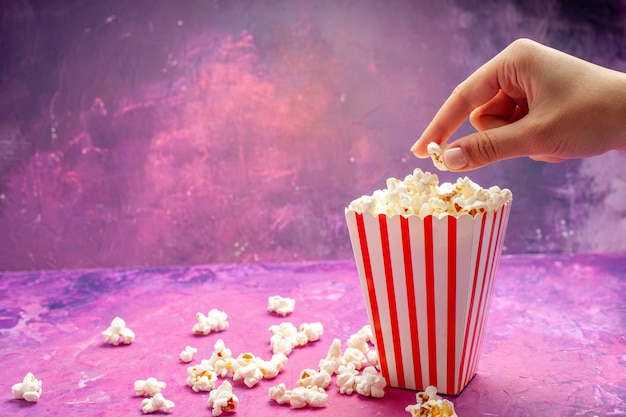 Frisches popcorn der vorderansicht auf hellrosa tischfarbkino-film