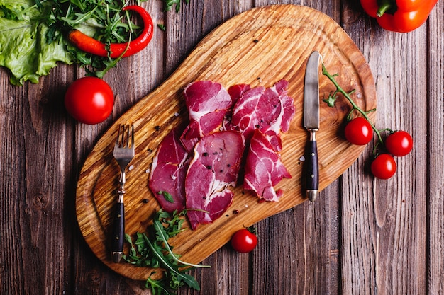 Frisches und gesundes Essen. Geschnittenes rotes Fleisch liegt auf dem Holztisch mit Arugula