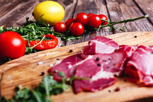 Frisches und gesundes Essen. Geschnittenes rotes Fleisch liegt auf dem Holztisch mit Arugula