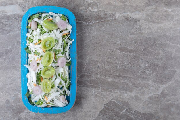 Frischgemüsesalat auf blauem Teller.