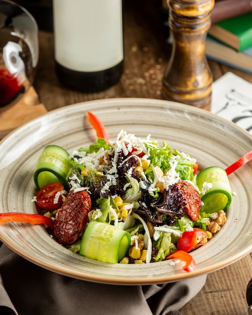 Kostenloses Foto frischgemüsesalat mit gurke, salat, getrockneten tomaten, mais und walnuss