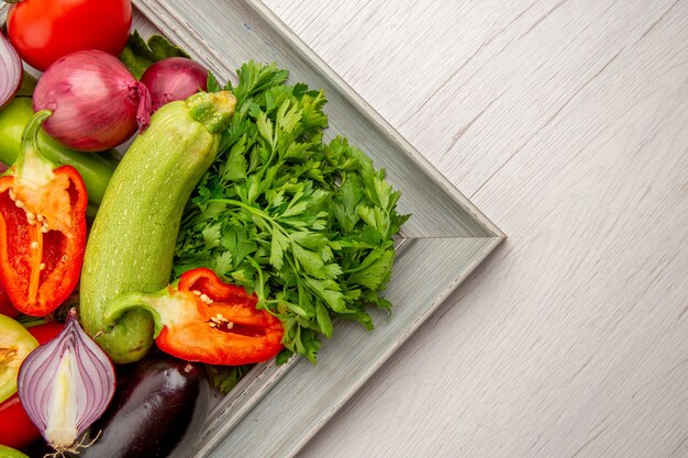 Frischgemüsezusammensetzung der Draufsicht mit Grüns innerhalb des Rahmens auf weißem Tisch