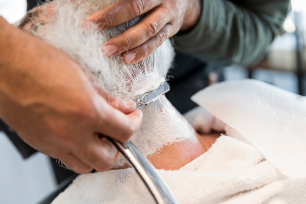 Friseur, der Bart zum Kunden rasiert