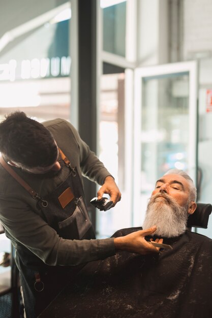 Friseur, der dem älteren Mann Bart rasiert