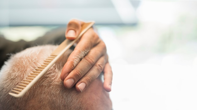 Friseur, der dem Kunden im Friseursalon Haar kämmt