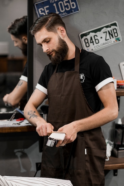 Friseur, der elektrischen Trimmer mit Bürste säubert