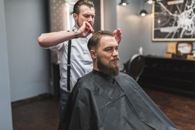 Friseur, der nasses Haar des Mannes anredet