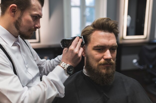 Friseur, der Tempel des Mannes rasiert