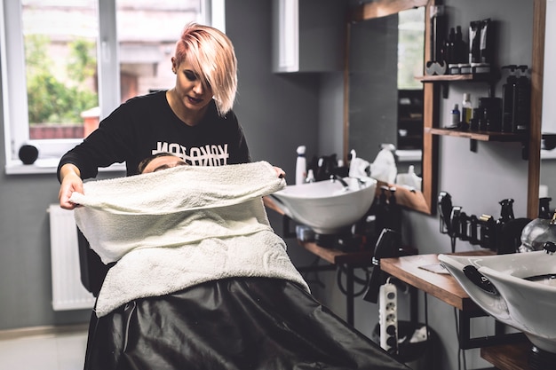 Friseur, der Tuch auf Gesicht des Kunden setzt