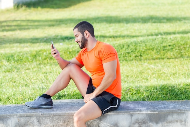 Fröhlich Läufer mit Telefon, um seine Ergebnisse zu analysieren