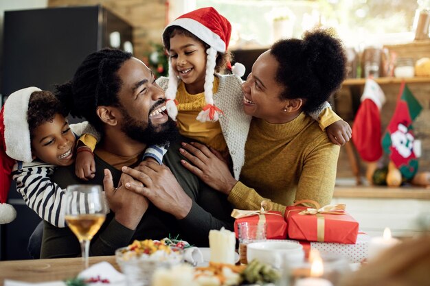 Fröhliche afroamerikanische Familie, die sich am Weihnachtstag zu Hause amüsiert