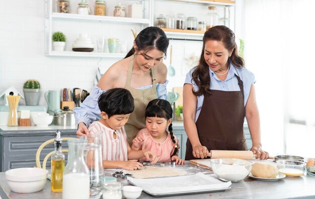 Fröhliche asiatische Familie bereitet Teig zu und backt Kekse in der Küche zu Hause Genießen Sie die Familie