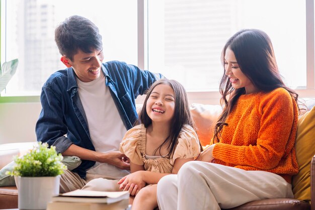 fröhliche asiatische familie spielen kitzeln eltern tochter lachen lächelnd spaß glück zusammen auf dem sofa im wohnzimmerentspannen beiläufige familienaktivitäten nach dem packen der sachen für den heimumzug beenden heimumzugsideen