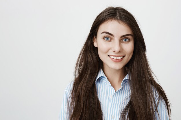 Fröhliche attraktive Frau mit langen dunklen Haaren und blauen Augen