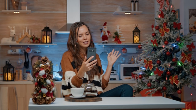 Fröhliche Frau beim Weihnachtsvideoanruf mit Freunden zu Hause