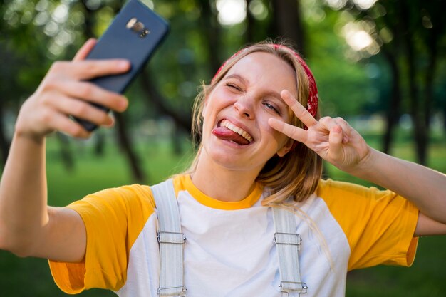 Fröhliche Frau, die selfie draußen nimmt