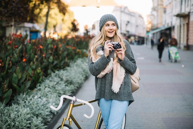 Fröhliche Frau mit Fahrrad und Kamera