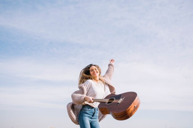 Fröhliche Frau mit Gitarre springen
