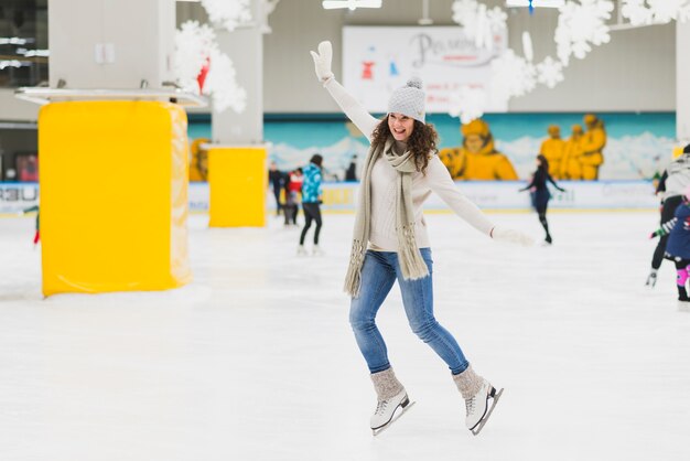 Fröhliche Frau Skaten auf Eisbahn