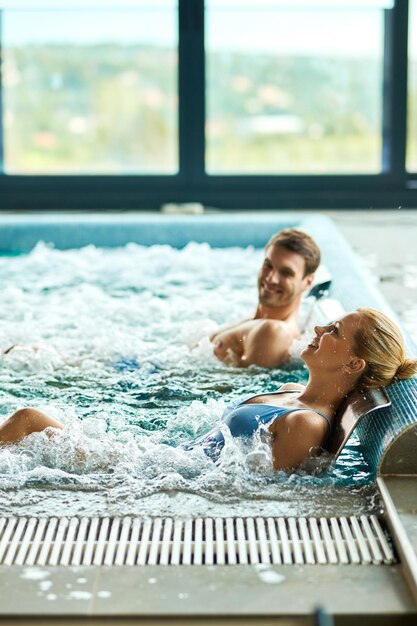 Fröhliche Frau und ihr Mann genießen eine Wassermassage im Thermalbad im Spa. Kopieren Sie Platz